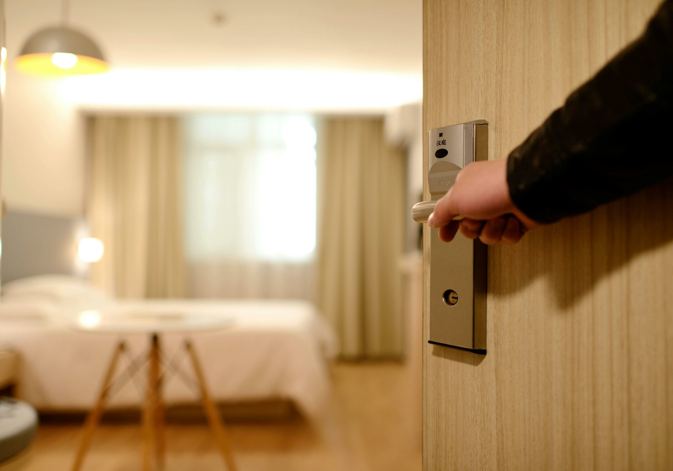 Hand opening the door to a hotel room used on a blog about the latest hospitality trends for 2025.