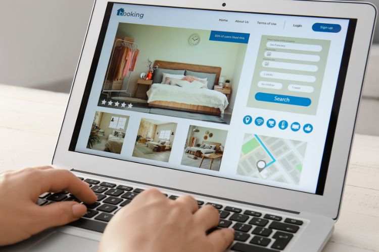 hands on a laptop keyboard viewing a hotel booking page with images of the room, a location map and reservation button used on a blog about hotel digital marketing