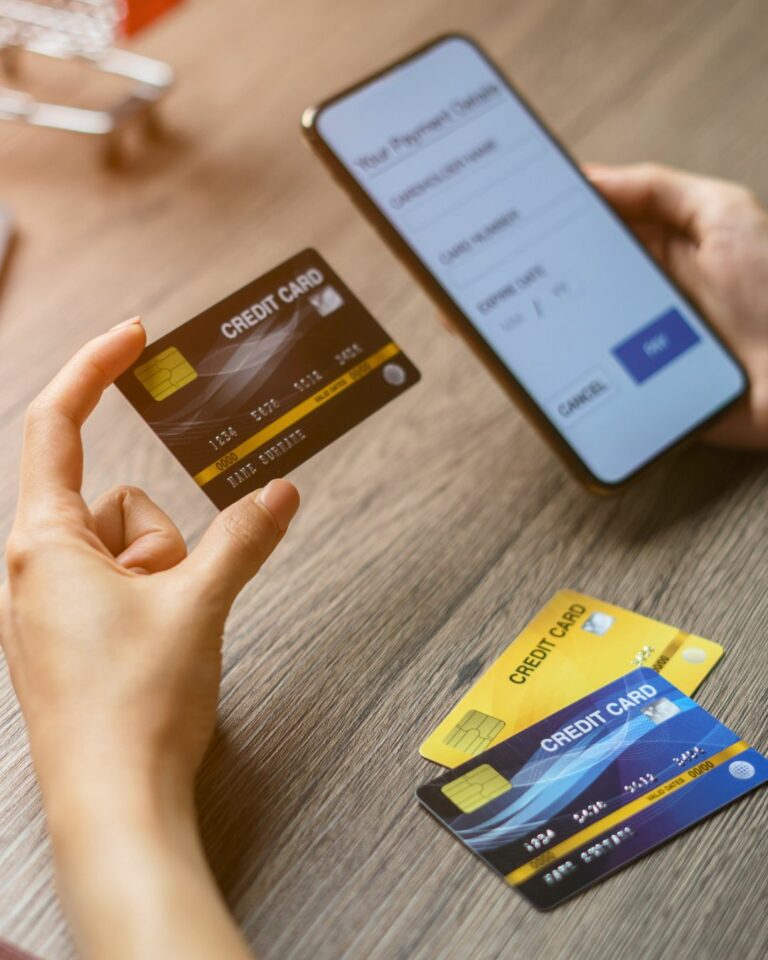 hands holding a credit card and a mobile device used on a blog about guest and merchant initiated transactions